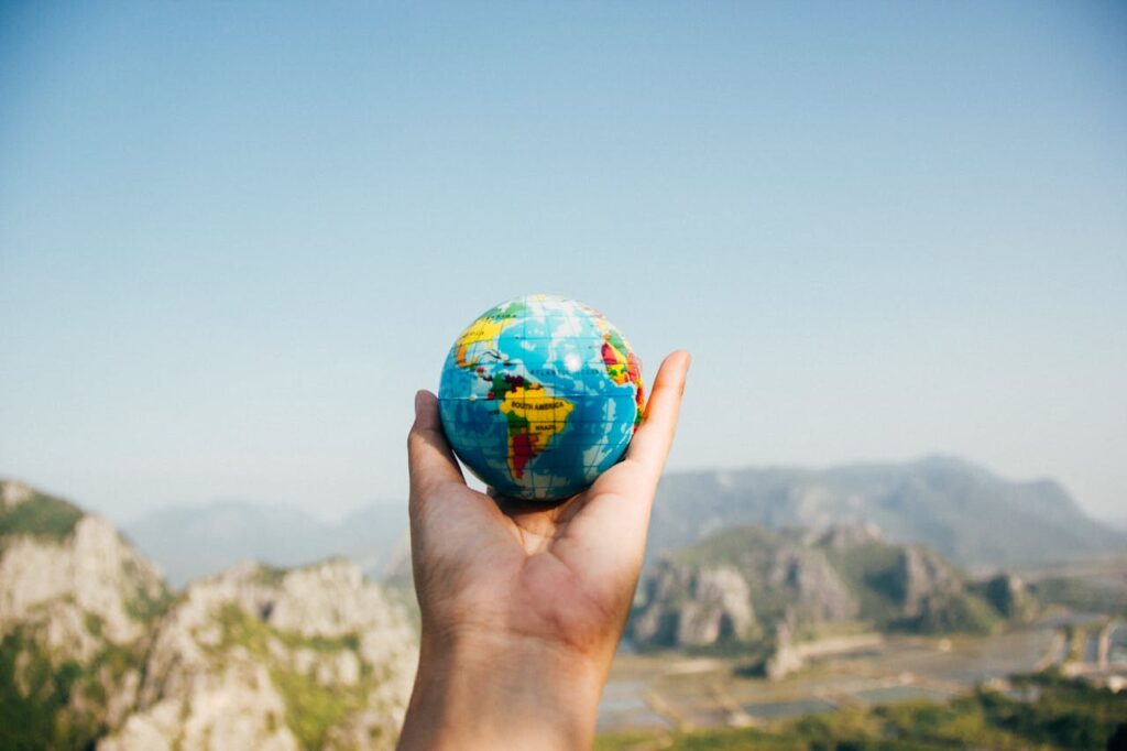pexels photo 346885 Hand holding a globe against a mountain background symbolizing travel and exploration.